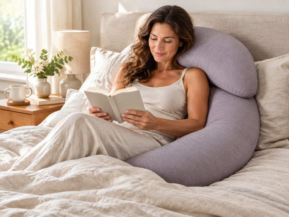 Woman reading in bed, propped against the curve of the Curlnest